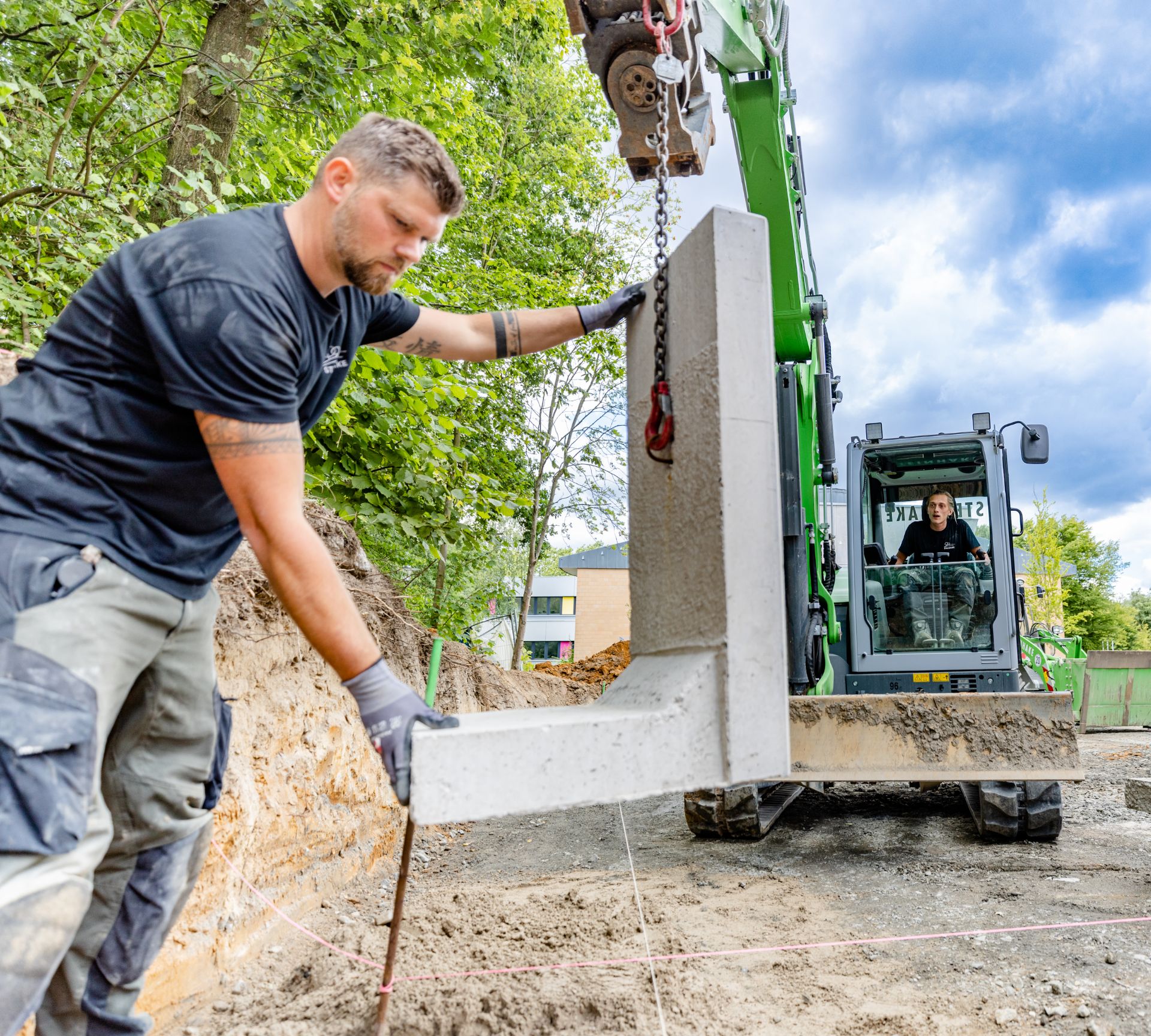 Steinhake Kolonne beim setzen der Randsteine auf einem Schulhof.