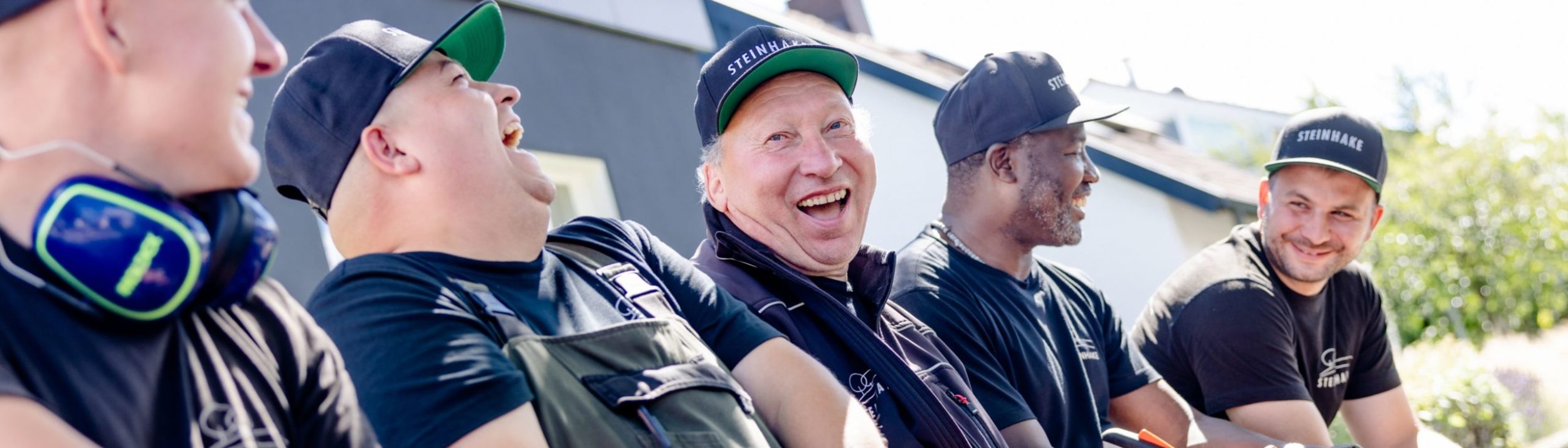 Grün & Pflege Team bei der Pause. Sie unterhalten sich und lachen dabei in die Kamera.